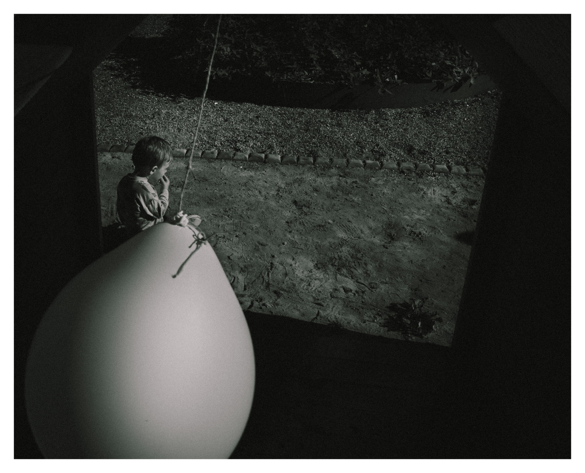 Child beside a large pale balloon in a dim room